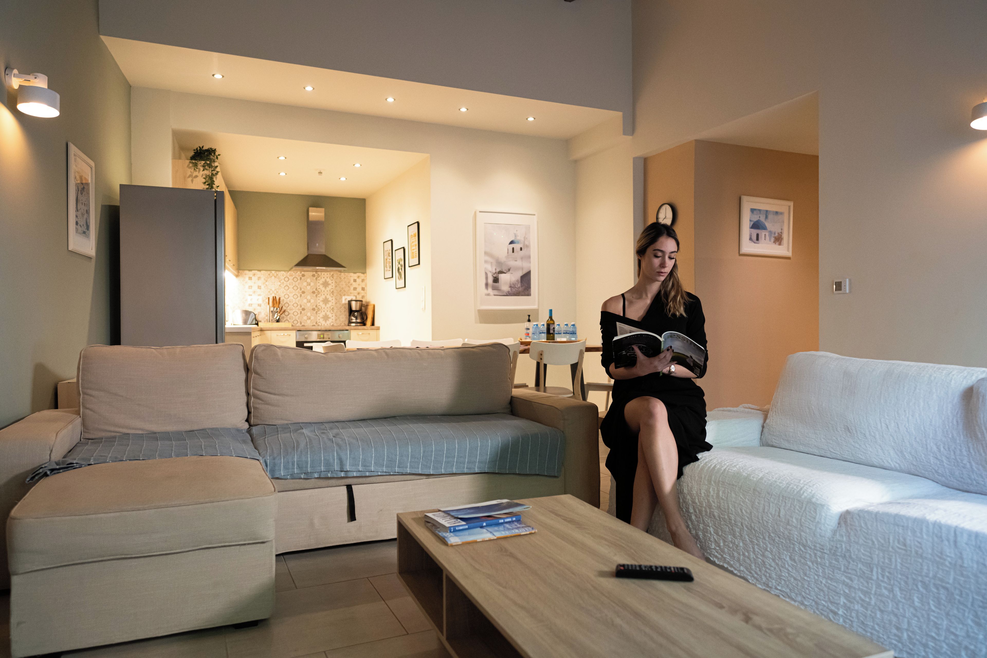 A modern living room with a sofa, a coffee table, and a kitchen in the background.