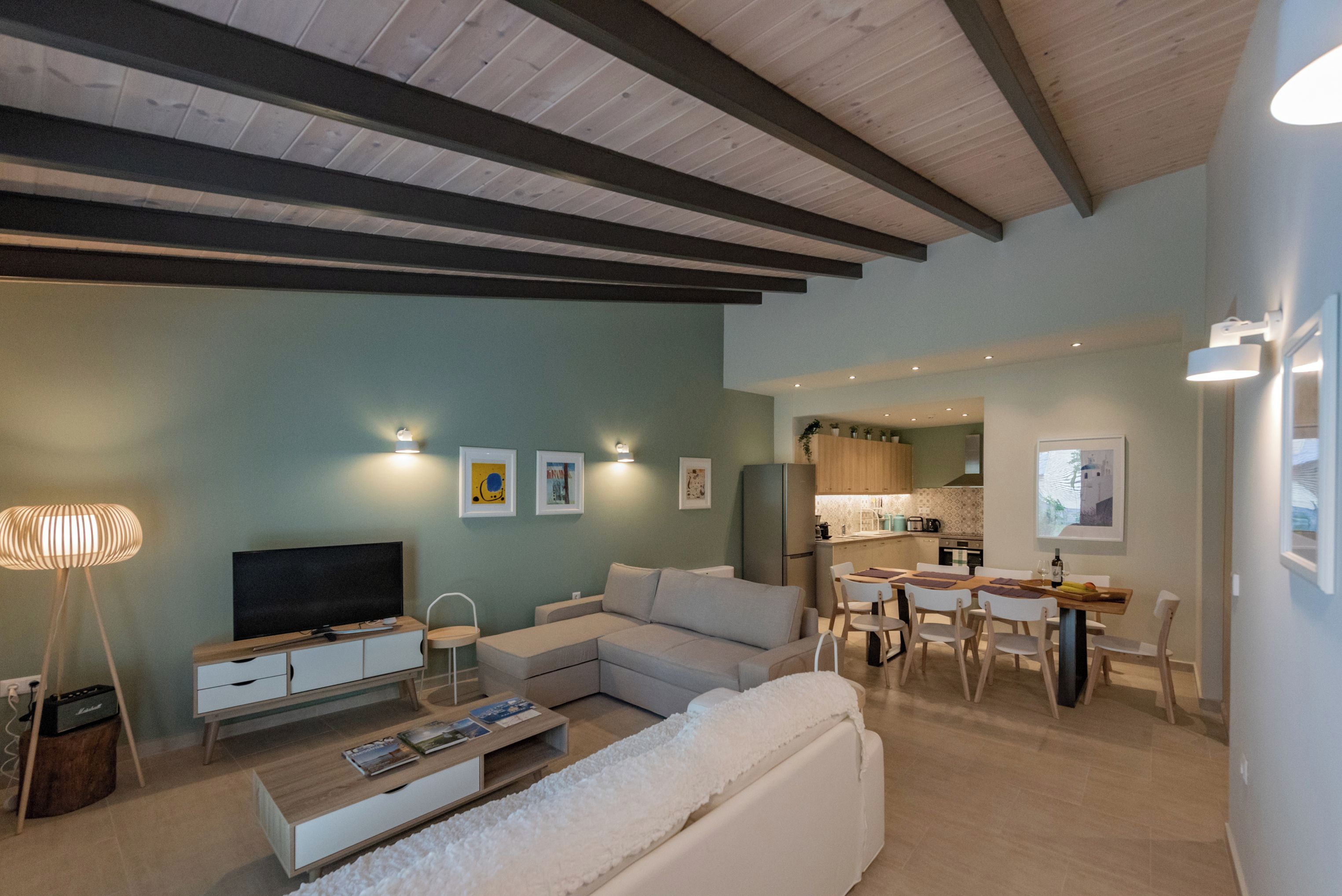 A modern living room with a sectional sofa, a TV, and a dining area with a table and chairs.