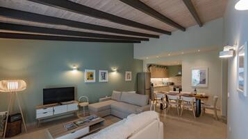 A modern living room with a sectional sofa, a TV, and a dining area with a table and chairs.
