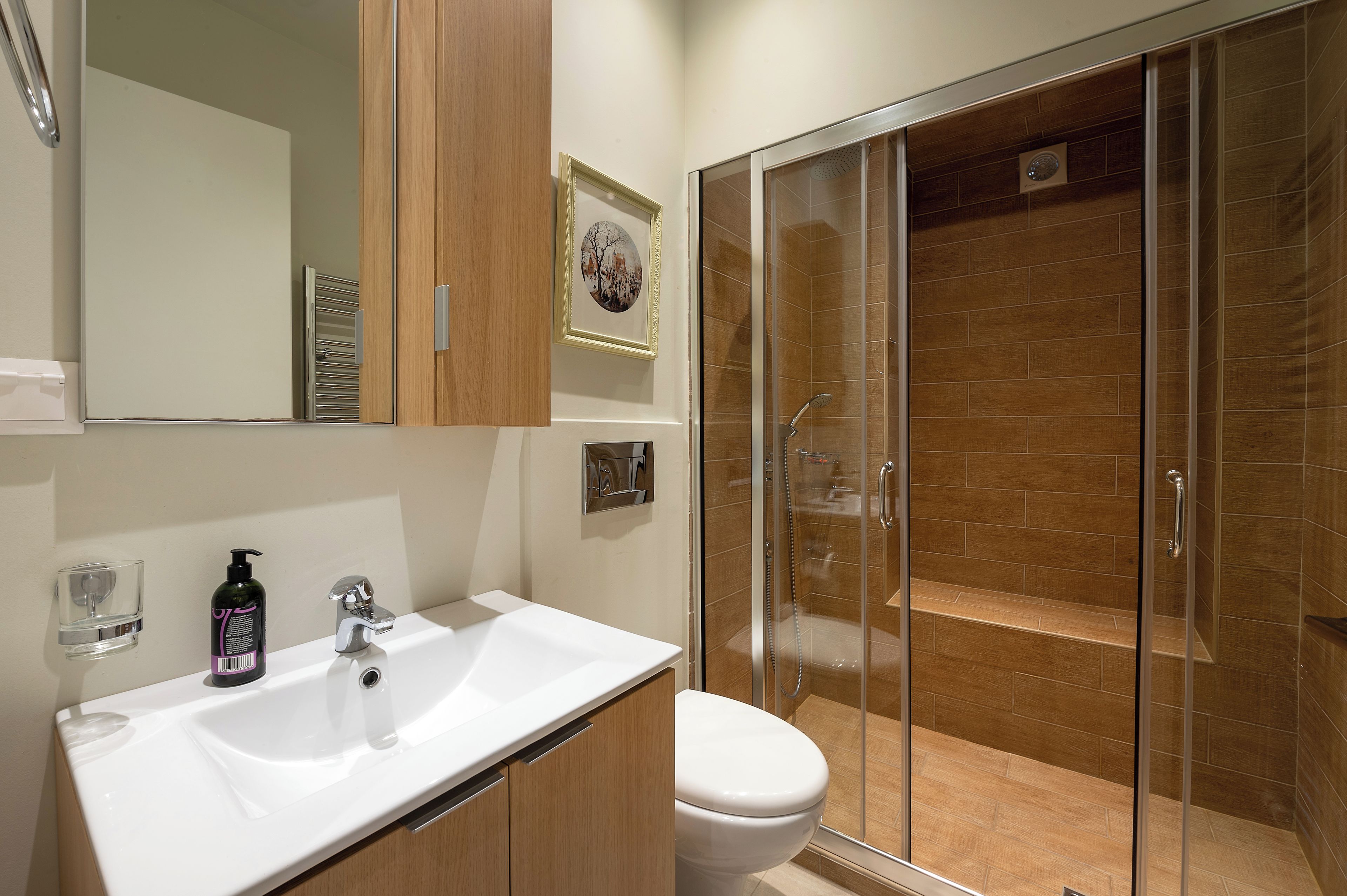 A modern bathroom with a white sink, a toilet, and a glass-enclosed shower.