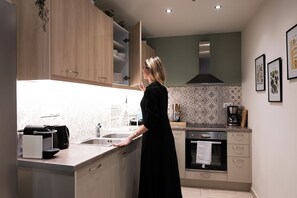 Una cocina moderna con armarios de madera, horno empotrado y cafetera.