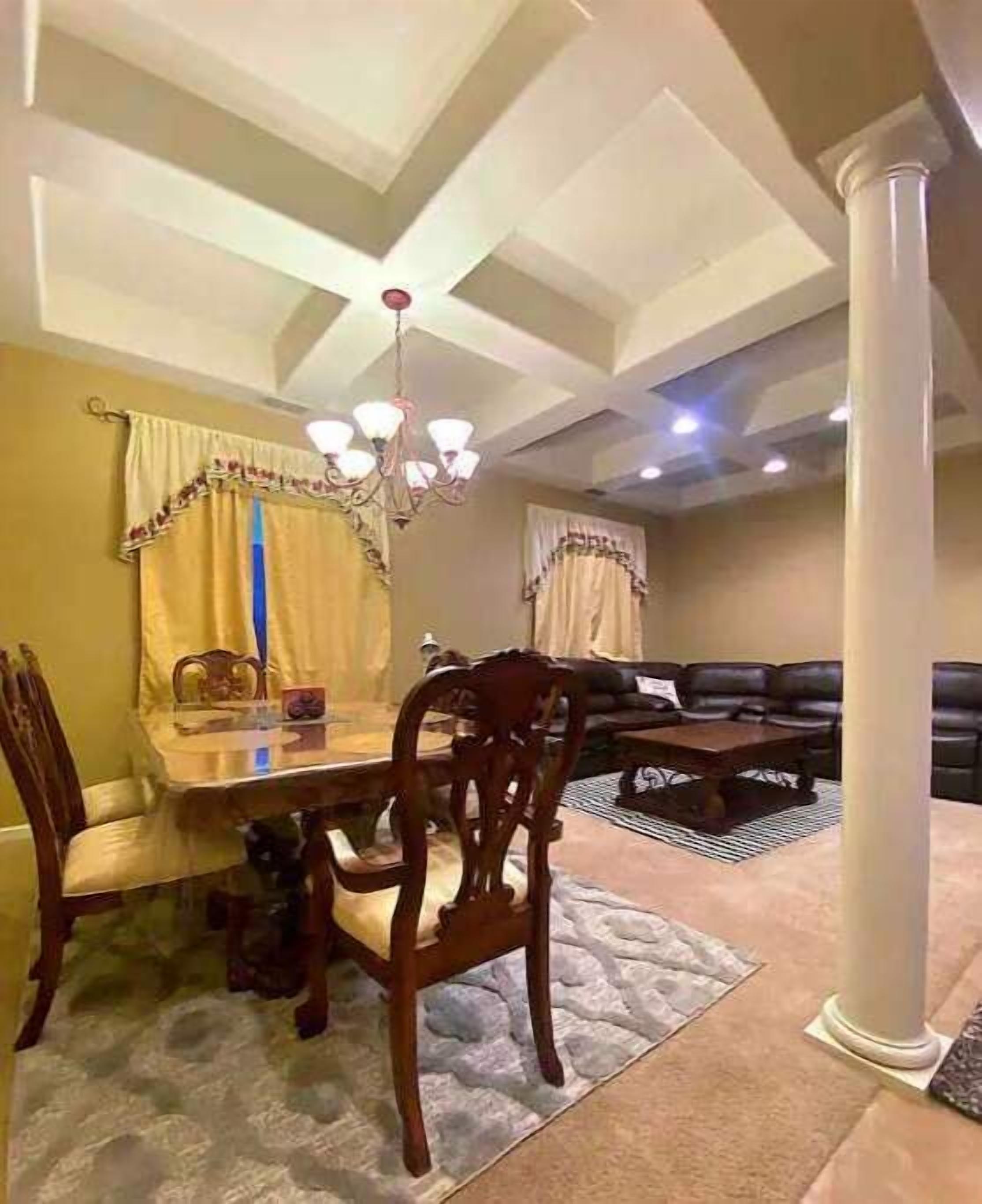 Il y a un coin repas avec une table, des chaises et un lustre. On y trouve également un salon avec un canapé et une table basse.
