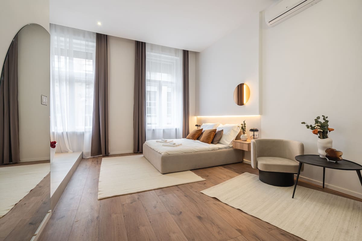 Une chambre à coucher moderne avec un grand lit, une table de chevet, une chaise et une petite table.