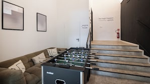 Ein modernes Interieur mit einem Tischfußballspiel, einer Couch und einer Treppe.