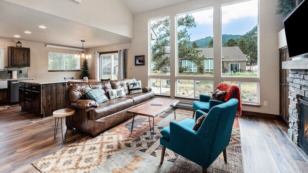 A spacious living room with a leather sofa, blue armchairs, and a fireplace. - Dog-Friendly! New Modern Home, Views & Wildlife (Estes Park)
