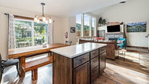 A modern kitchen with a wooden island, large windows, and a dining area with a bench. - Dog-Friendly! New Modern Home, Views & Wildlife (Estes Park)