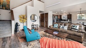 A spacious living room with a high ceiling, a staircase, a kitchen, and a dining area. - Dog-Friendly! New Modern Home, Views & Wildlife (Estes Park)
