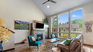A spacious living room with a fireplace, large windows, and a view of the outdoors. - Hot tub! Dogs OK! Views, near park! (Estes Park)