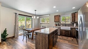 A modern kitchen with a central island, wooden cabinets, and a stainless steel refrigerator. - Hot tub! Dogs OK! Views, near park! (Estes Park)