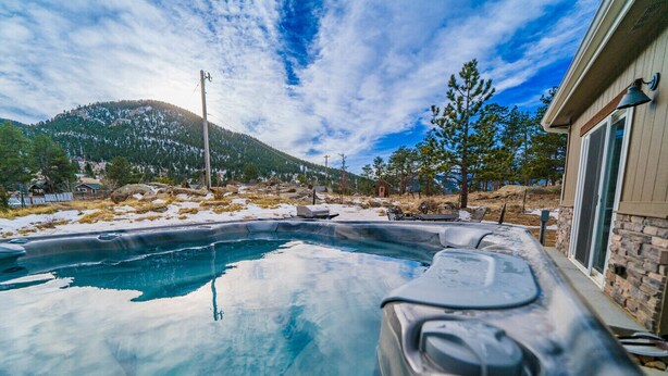 A hot tub with a view of a mountainous landscape and a house with stone walls. - Hot tub! Dogs OK! Views, near park! (Estes Park)
