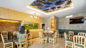 A restaurant with wooden chairs and tables, a green counter, and a ceiling mural. - Forest Villas Guest House (Leiria)