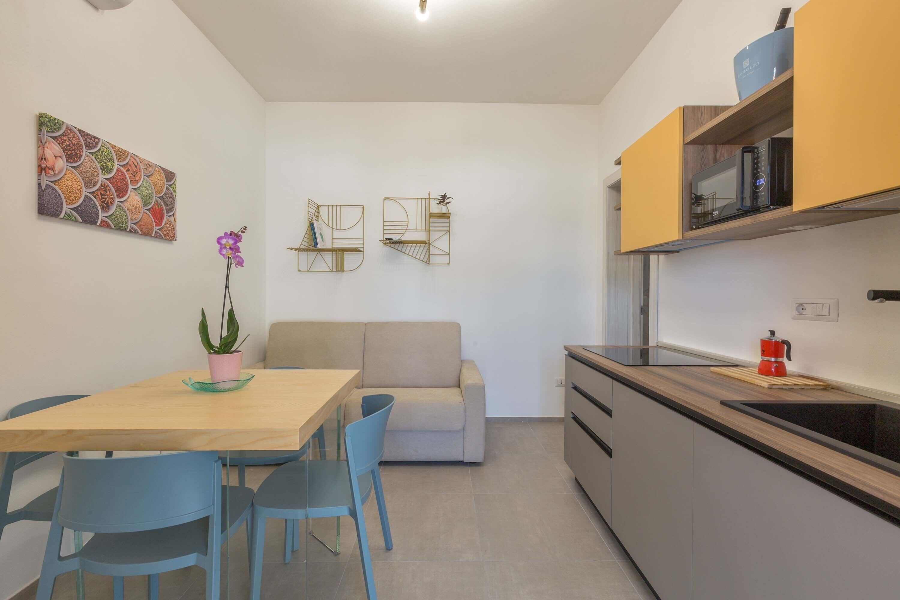 A compact living space with a dining area, kitchenette, and a sofa.