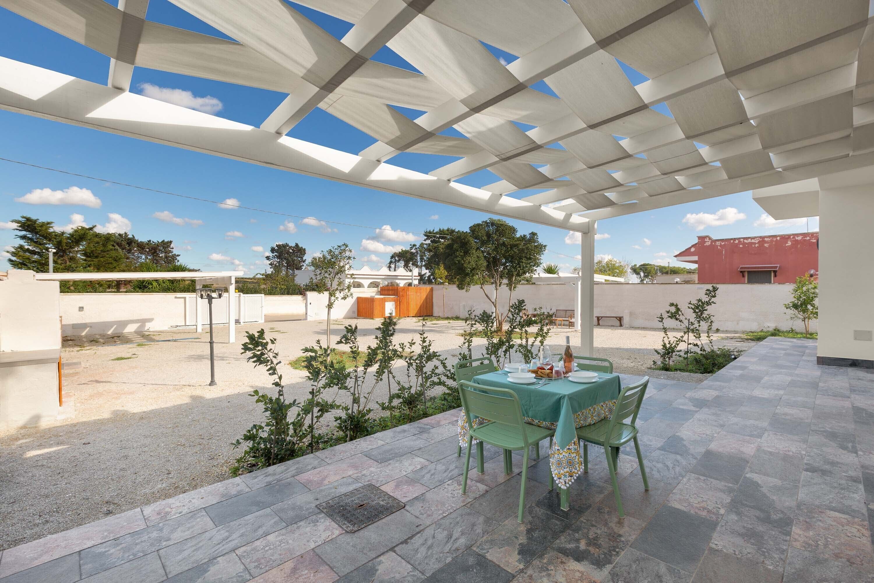 Une terrasse extérieure avec une table dressée pour le repas, entourée de verdure et sous un ciel dégagé.