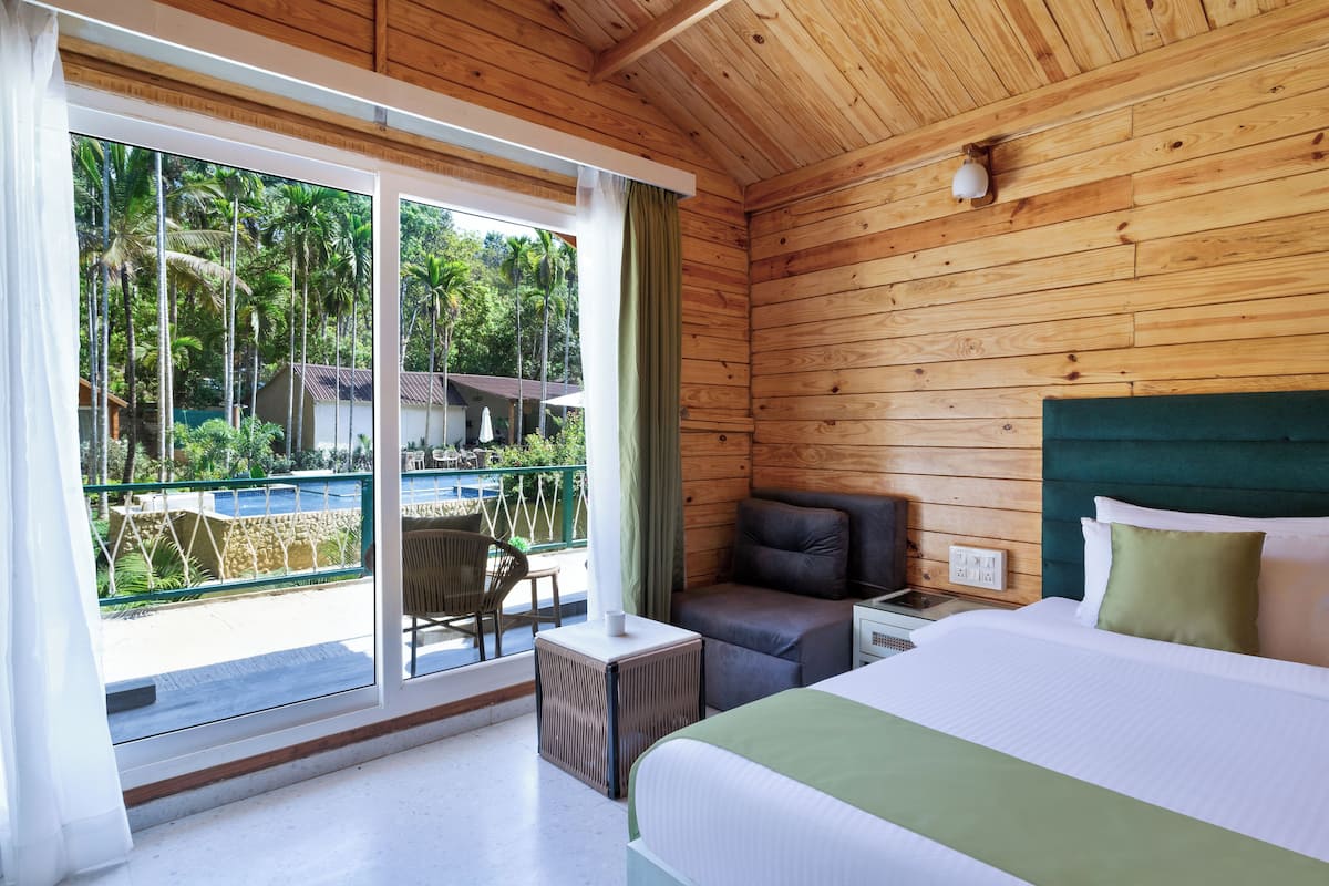 A room with a bed, a desk, and a chair. There is a window with a view of palm trees and a pool.