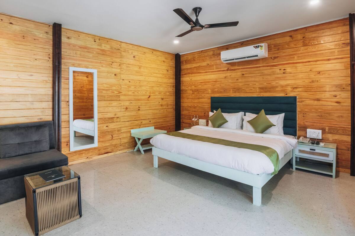 A bedroom with a bed, bedside table, nightstand, and a mirror.