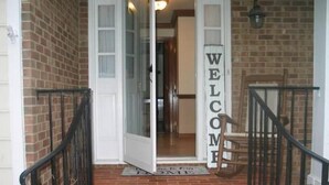 Eine Ziegelhausfassade mit einer weißen Tür und einem 'WELCOME'-Schild.