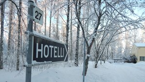 A sign for 'HOTELLI' with a directional arrow, set against a snowy landscape with trees and a building in the background. - Hotelli Immalanjärvi (Imatra)
