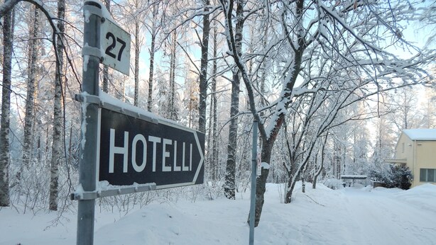 A sign for 'HOTELLI' with a directional arrow, set against a snowy landscape with trees and a building in the background. - Hotelli Immalanjärvi (Imatra)