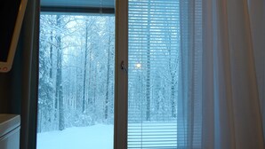 A room with a large window revealing a snowy forest view. - Hotelli Immalanjärvi (Imatra)