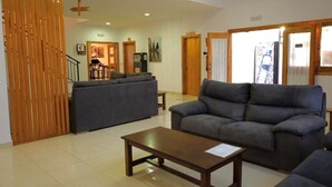 Amplia sala de estar con un juego de sofás, una mesa de centro de madera y un comedor al fondo.