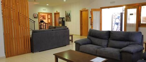 Amplia sala de estar con un juego de sofás, una mesa de centro de madera y un comedor al fondo.