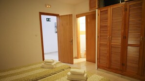 Habitación de hotel con dos camas, armarios de madera y una puerta de salida visible.