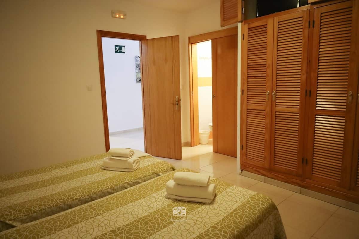 A hotel room with two beds, wooden wardrobes, and a visible exit door.