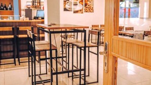 Un interior moderno con una zona de bar, mesas y sillas de madera.