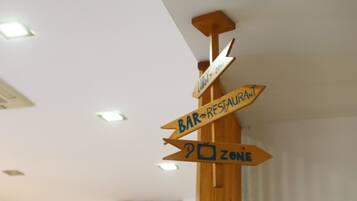 A wooden signpost with directional arrows pointing to different areas such as "Lobby Zone" and "Bar-Restaurant Zone".