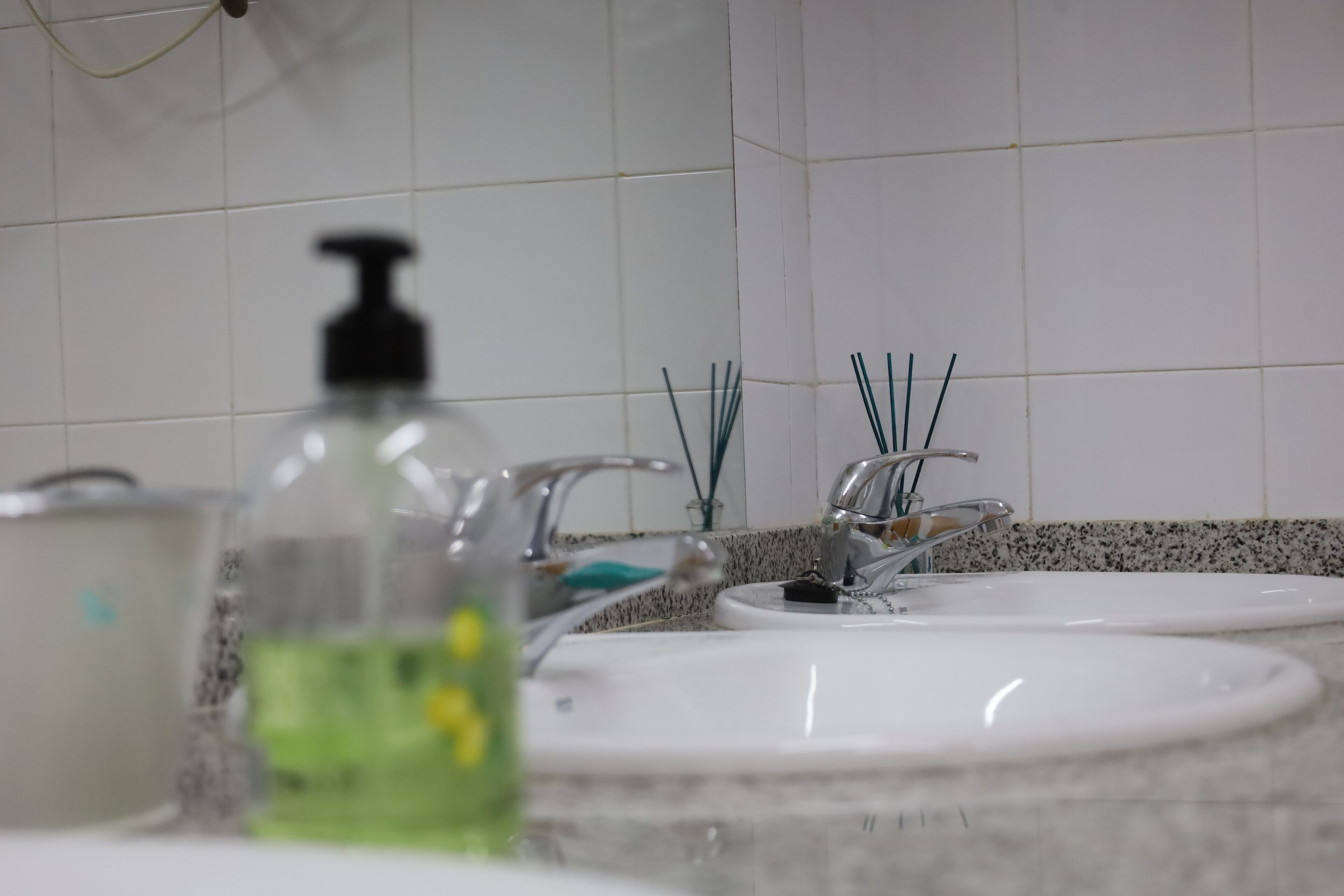 A bathroom with two sinks, a mirror, and a soap dispenser.