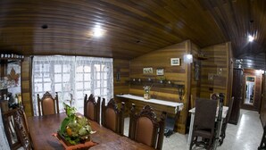 A dining area with a wooden ceiling, a table with a centerpiece, and chairs. - Recanto Monte Suíço (Campos do Jordão)