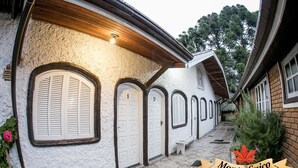 A building with white walls, multiple doors, and a bench. - Recanto Monte Suíço (Campos do Jordão)