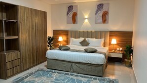 Un dormitorio moderno con una cama grande, dos mesitas de noche con lámparas, un armario de madera y arte abstracto en la pared.