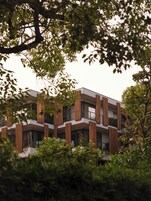 Un bâtiment moderne doté de nombreux balcons, entouré d’une végétation luxuriante.