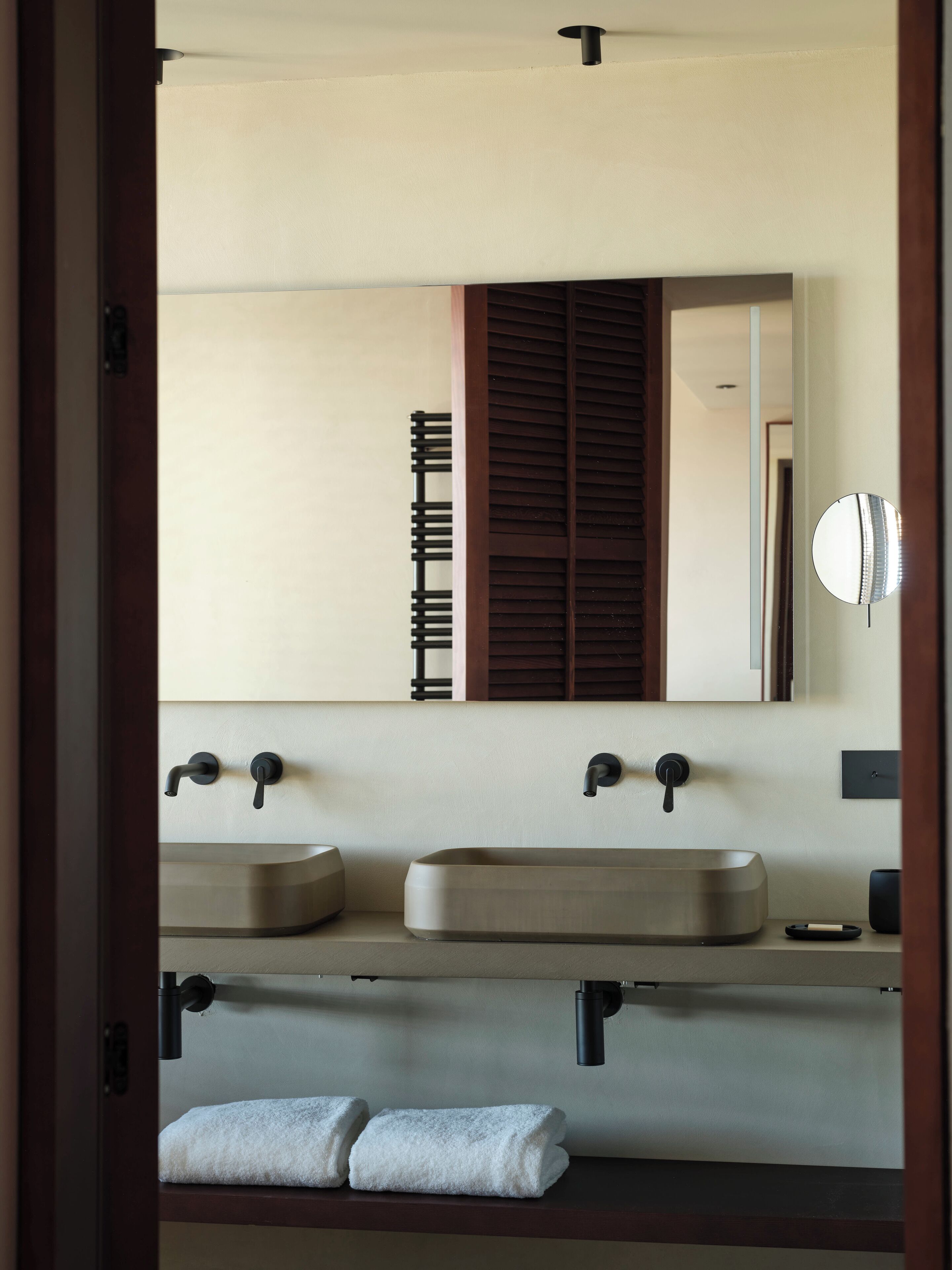 Un baño con dos lavamanos, un espejo y un perchero para toallas.