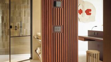 Une salle de bain moderne avec un séparateur en panneaux de bois, une douche en verre, un lavabo avec un porte-serviettes et un tabouret.