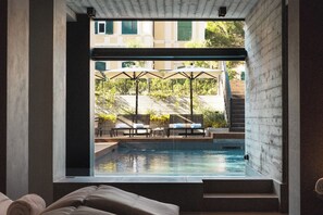A modern hotel room with a view of an outdoor swimming pool, lounge chairs, and umbrellas.