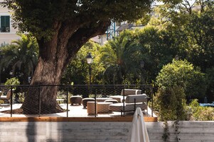 Un espace extérieur aménagé avec un grand arbre, des fauteuils confortables et une clôture.