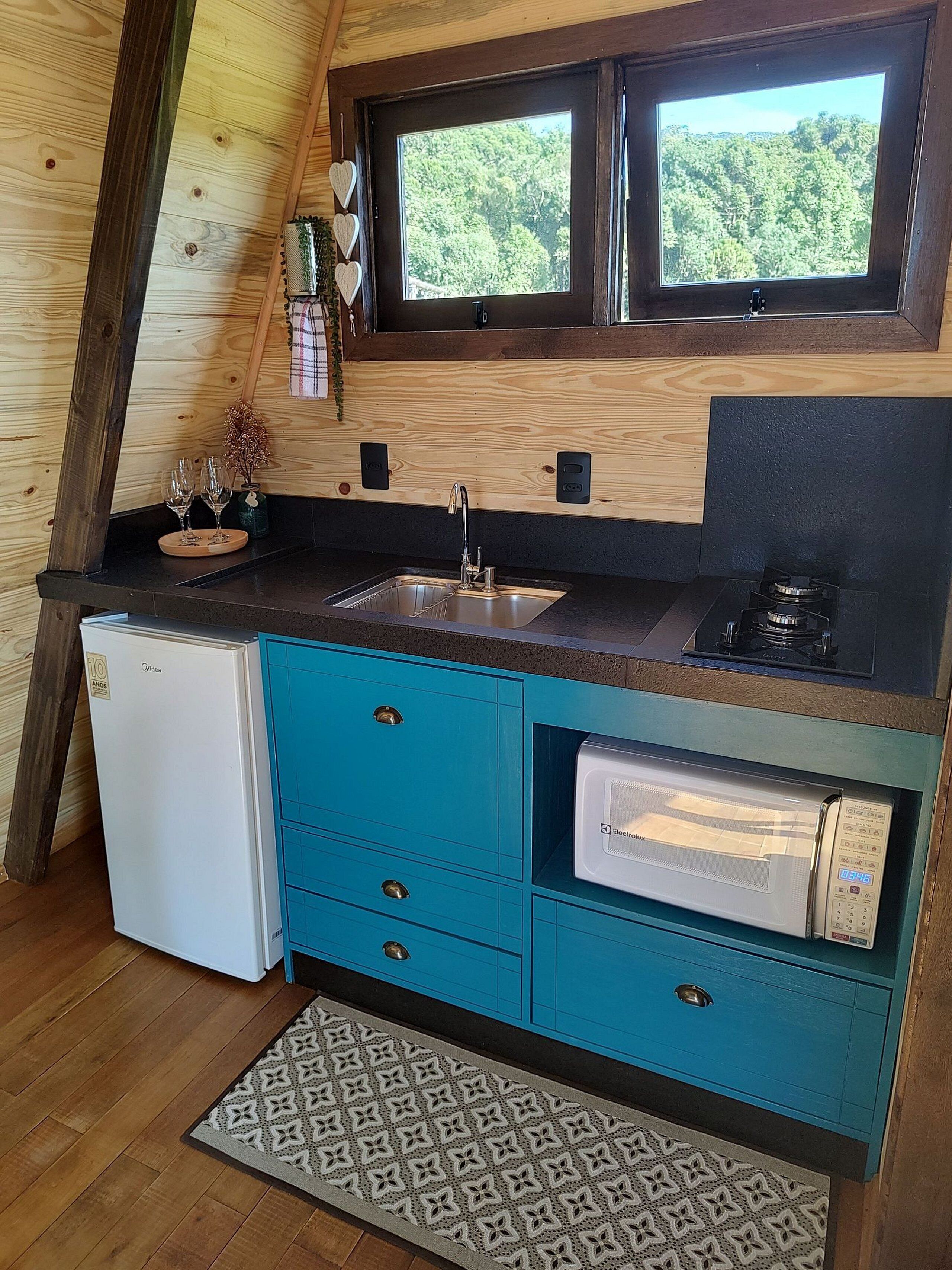 A compact kitchen with a sink, a small refrigerator, and a microwave.