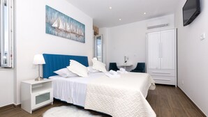 A bedroom with a bed, nightstand, and a painting of sailboats on the wall.