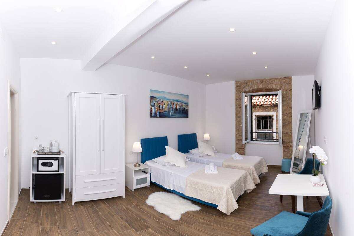 A modern hotel room with a large bed, two bedside tables, a desk, a wardrobe, and a painting on the wall.