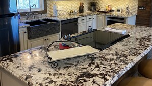 A modern kitchen with granite countertops, a stainless steel refrigerator, and a built-in oven. - Lavender Farm Private Luxury Suite (South Kingstown)
