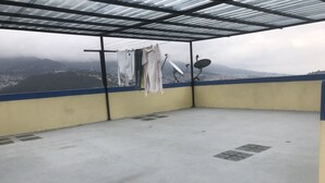 A balcony with a metal roof, clothes hanging on a line, and satellite dishes. - Suite Toty EN Renta (Quito)