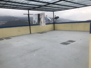 A balcony with a metal roof, clothes hanging on a line, and satellite dishes.