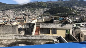 A densely populated urban area with a mix of residential and commercial buildings, a prominent mountain range in the background, and a clear blue sky. - Suite Toty EN Renta (Quito)