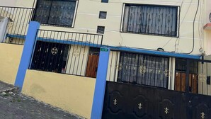 A multi-story building with a flat roof, a balcony on the upper floor, and a gated entrance with decorative metalwork. - Suite Toty EN Renta (Quito)