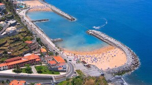 Vista aérea de un pueblo costero con playa, un puerto deportivo y edificios residenciales.