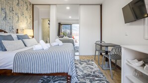 Una habitación de hotel moderna con una cama grande, un escritorio y un televisor.