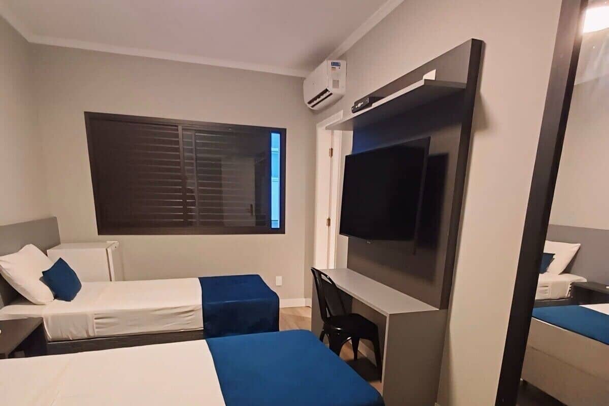Une chambre d’hôtel avec deux lits, un bureau, une télévision et un grand miroir.