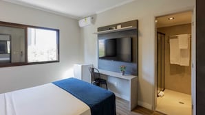 Une chambre d’hôtel moderne équipée d’un lit, d’un bureau, d’une télévision et d’un espace douche.